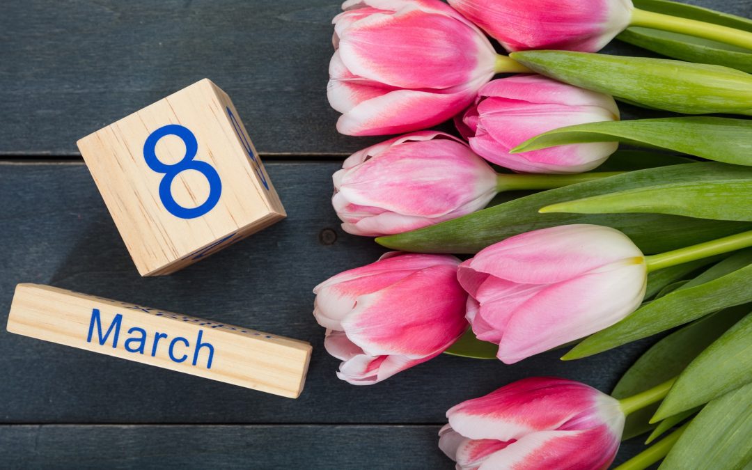 Women's day concept. Pink tulips and the March 8th date on blue background